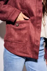 Sobrecamisa color borgoña de gamuza sintética con cuello camisero, cierre frontal con botones a tono, bolsillos de parche con solapa en el pecho y mangas largas con puños abotonados.
