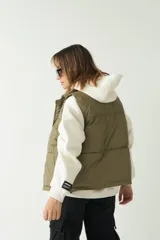 Chaleco puffer color verde oliva con cuello alto y cierre frontal con cremallera.