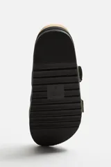 Sandalias planas color beige con doble tira ancha en el empeine y cierre con hebilla.
