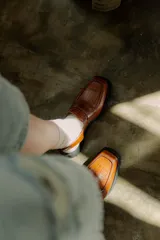 Zueco tipo mocasín color marrón con textura croco y tira regulable al talón.