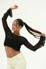 Top negro de manga larga, confeccionado en tejido de encaje transparente con textura, corte cropped y campana en los puños.
