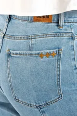 Jean de mezclilla azul claro, tiro medio, corte recto con leve campana al tobillo. Presenta costuras verticales marcadas en el frente y en los laterales de las piernas, y terminación deshilachada en el ruedo.