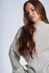 Sweater color crema de punto trenzado, con cuello alto y mangas largas.