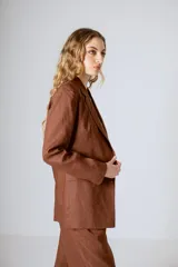 Blazer marrón con solapas de muesca, cierre frontal con botones y corte recto.