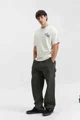 Remera de manga corta color crema con estampado en la espalda que incluye flores azules, texto "All Day Every Day The Good Vibes Crew Mistral" y texto "Feel Good" en el lateral.