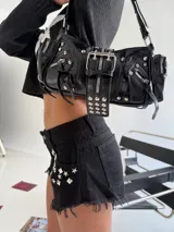 Cartera bandolera negra con múltiples hebillas, tachas y cierres.