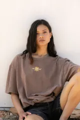 Remera negra de corte oversize con estampa trasera con un sol y texto en color naranja.