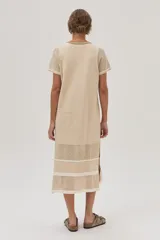 Vestido midi de tejido de punto color beige, con escote redondo, mangas cortas, tajos laterales y diseño con patrón de puntos calados y rayas.