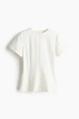 Remera blanca entallada de punto pesado interlock, con cuello redondo, mangas cortas, pinzas moldeadoras en la cintura y bajo acampanado.