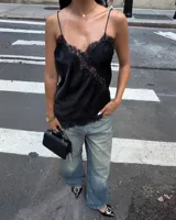 Top lencero de seda negro con escote en V adornado con encaje floral en el borde y en paneles laterales. Posee tirantes finos ajustables.