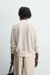 Sweater color crema de punto, con cuello polo y mangas largas. Tejido en hilatura de cáñamo con acabados en rib.