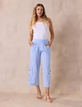 Pantalón blanco de algodón con pretina elastizada, bolsillos inclinados y ruedo lateral con tajo y botones.