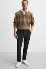 Pantalón negro de corte slim fit, confeccionado en tejido elástico. Cuenta con cintura elástica, bolsillos frontales y traseros de vivo. Cierre frontal con cremallera y botón.