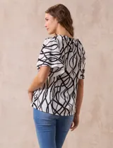 Blusa blanca estampada con líneas y lunares negros, de crepe marca Alex & Parker. Tiene cuello a la base, escote en V con botón y mangas cortas amplias.