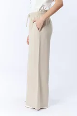 Pantalón beige de corte palazzo con cintura elastizada y cordón ajustable.