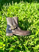 Bota corta de cuero marrón con detalles en gamuza azul marino, cierre metálico lateral y hebilla decorativa.