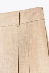 Bermudas color beige de tiro alto con trabillas en la cintura, pinzas en el delantero y cierre lateral con cremallera oculta.