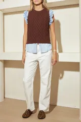 Chaleco marrón de punto con diseño trenzado, cuello redondo y sisas con volantes celestes.