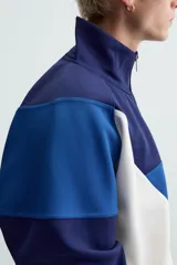 Chaqueta deportiva azul marino, azul y blanca con cuello alto, cierre frontal con cremallera, bolsillos laterales y puños y bajo acanalados.
