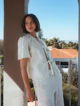 Camisa a rayas verticales color blanco y gris, con escote en V, mangas cortas abullonadas y cierre con lazo.