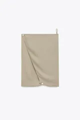 Vestido largo color beige topo, con escote halter y profundo escote pico pronunciado. Presenta un diseño drapeado con volumen en la zona del busto y espalda descubierta.