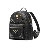 Mochila negra con monograma de la marca MCM estampado en toda la superficie y tachuelas metálicas doradas y plateadas. Cuenta con cierre bidireccional, asa superior reforzada, correas ajustables, dos compartimentos interiores, bolsillos laterales y placa metálica con el logo de la marca en el frente.