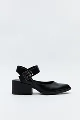 Zapato negro tipo zueco con acabado charol, tira ancha con hebilla metálica y taco ancho de altura media.