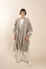 Ruana marrón con diseño a cuadros blancos, terminación envivada y flecos cortos.