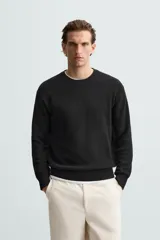 Jersey color crema de punto perlado, con cuello redondo, manga larga y corte regular fit.