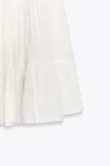 Vestido corto color salmón, de escote recto y tirantes finos ajustables. Presenta detalle de encaje en el escote y falda de tres niveles.