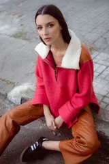 Buzo de lana color beige con cuello alto con cierre y aplique de corderito en el cuello. De mangas rectas y corte amplio.