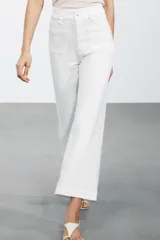 Pantalón de jean celeste de tiro alto y corte wide leg, con bolsillos frontales y traseros, cierre frontal con cremallera y botón metálico.