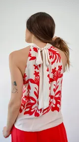 Top de seda estampado en blanco y rojo, con cuello halter y lazo en la espalda.