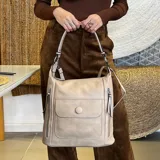Cartera negra de símil cuero con doble cierre superior, bolsillo frontal con tapa y broche magnético, bolsillos laterales con cierre y correa larga regulable y desmontable.