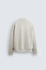 Cazadora bomber negra de corte regular, confeccionada en tejido con efecto ante. Cuenta con cuello, puños y bajo de rib elástico, bolsillos de vivo en la cadera y cierre frontal con cremallera.