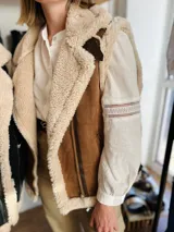 Chaleco color camel confeccionado en gamulan, sin mangas y con cuello solapa.