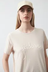 Remera blanca de algodón de manga corta, con cuello redondo y bordado frontal en hilo color beige claro con la palabra "J'adore" en tipografía cursiva.
