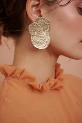 Aros colgantes dorados con forma de tres círculos irregulares texturizados.