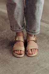 Sandalias bajas doradas de cuero, con dos tiras anchas en el empeine y hebilla lateral ajustable.