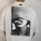 Remera negra de corte oversize y mangas cortas, con estampa en la espalda de una fotografía en blanco y negro de una persona fumando.