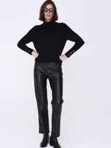 Sweater negro de cuello alto, mangas largas con botones decorativos en los puños y corte ajustado.
