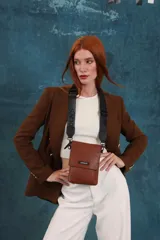 Bandolera tipo phone bag pequeña, color marrón claro, con correa de galón regulable. Tiene un compartimento principal y un bolsillo adicional con tapa.
