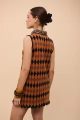 Vestido corto sin mangas con estampado de rombos en amarillo, azul y rojo. Tiene escote con abertura en forma de gota y ruedo con terminación en picos.