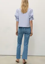 Pantalón de jean celeste de corte cropped y estilo flare, con tiro medio, cinco bolsillos, trabillas y bajo deshilachado.
