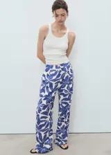 Pantalón largo de tiro medio, corte recto, con pinzas frontales y estampado floral grande en tonos azul y blanco crema.