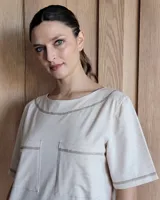 Vestido midi negro con cuello redondo y mangas cortas. Presenta dos bolsillos cuadrados en el pecho y ribetes blancos en cuello, mangas, bolsillos y ruedo.