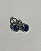 Aritos colgantes con dije circular de resina azul con glitter y borde de strass plateado.