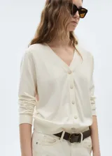 Cárdigan color crema de tejido de punto fino con cuello en V, cierre frontal con botones y mangas largas.