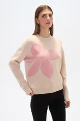 Sweater color beige con estampado de flor rosa, de corte ancho y cuello redondo.