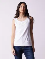 Blusa blanca sin mangas de seda fría, con cuello redondo y apliques de flores blancas.